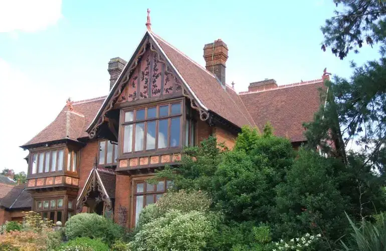 Clay-tiled pitched roofs and gables on a large period house in Loughton