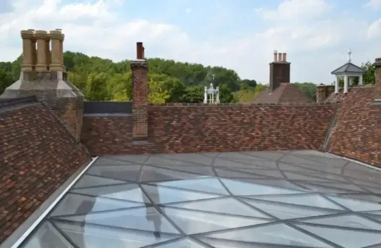 Glazed roof lantern set among tiled roofs and chimneys at Toddington Manor